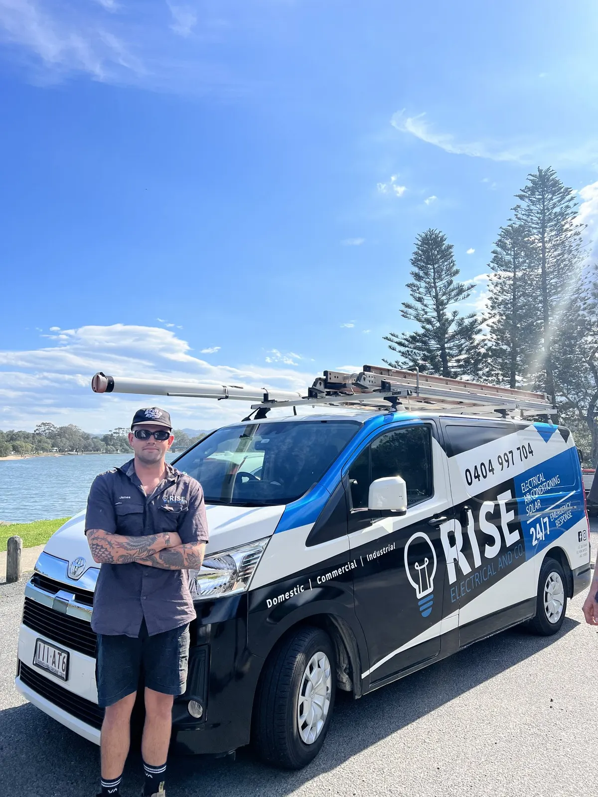 James from Rise Electrical and Co standing in front of the Rise van by the water