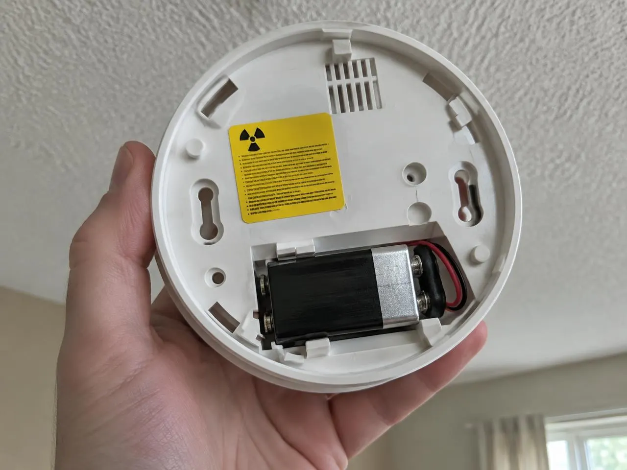 Back of an ionisation smoke alarm with yellow radiation warning sticker